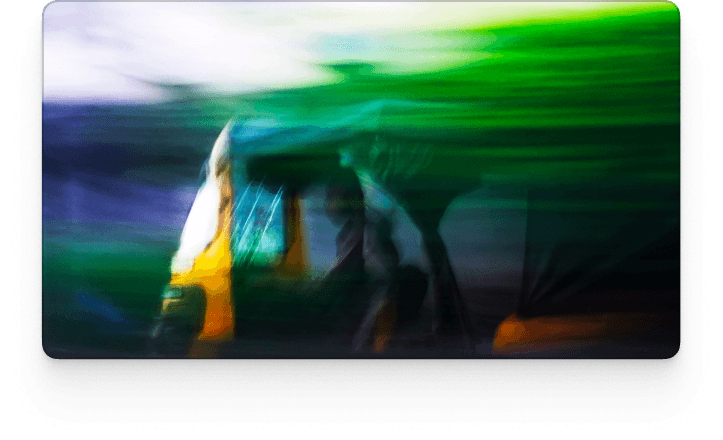 A motion-blurred street scene featuring a yellow and green vehicle